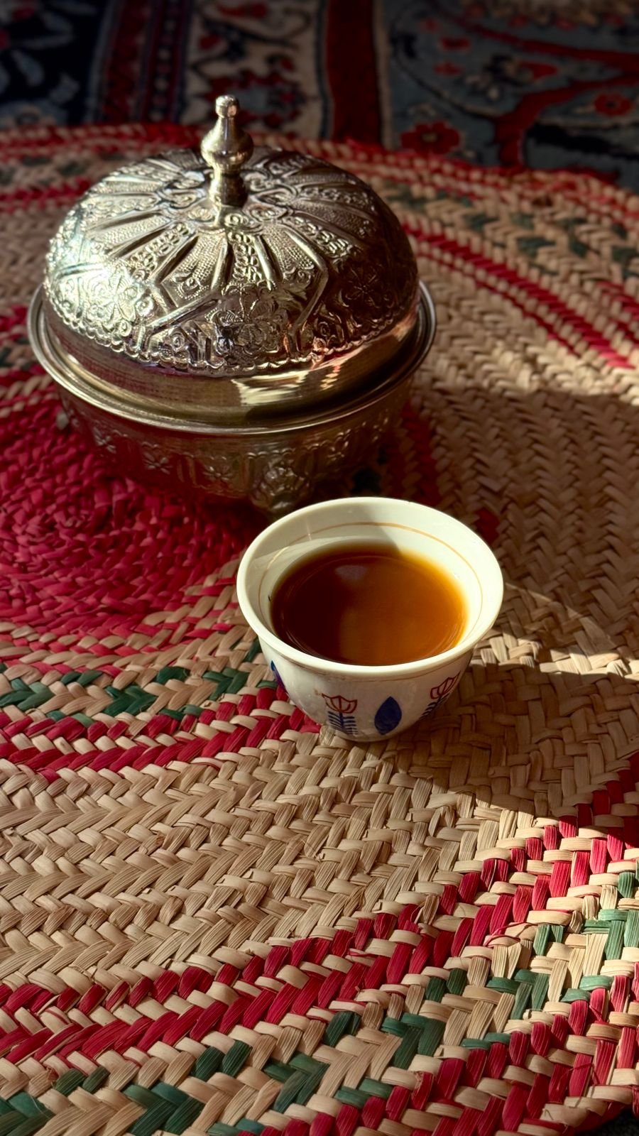 Traditional Arabic coffee set with an ornate pot on a woven mat